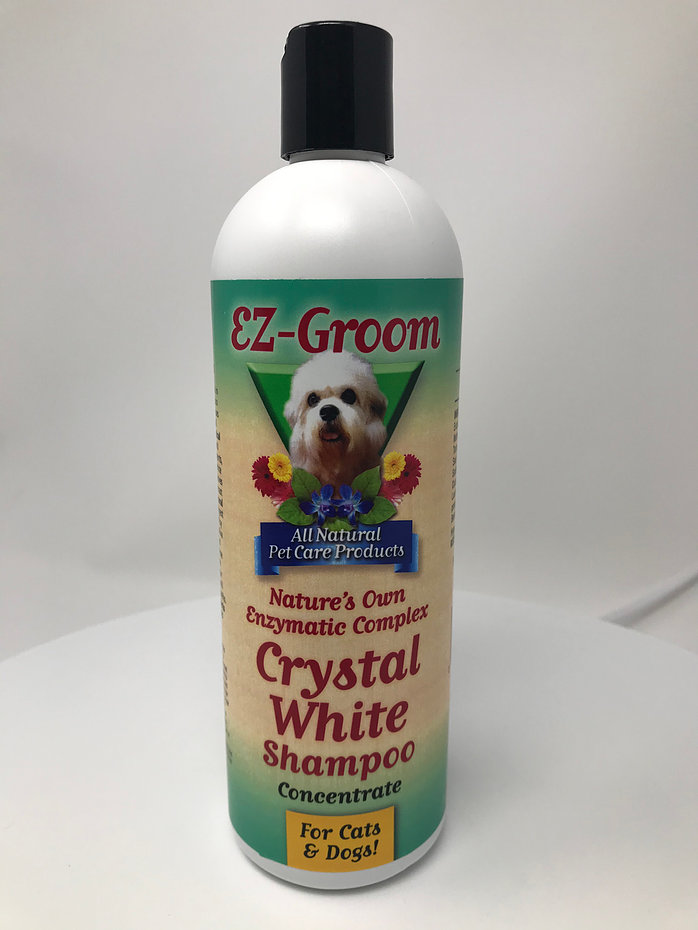 EZ-Groom Crystal White Enzyme - шампунь «Белый кристалл» предназначен для использования на шерсти белых и цветных животных (для собак и кошек).  Благодаря специальным ферментам эффективно удаляет пятна от слез, мочи, травы, крови и других органических загрязнений. Моющая кокосовая основа способствует эффективному удалению жировых загрязнений. Наличие увлажняющих компонентов помогают сделать шерсть объемной и послушной. Наличие специальных оптических компонентов придает белому цвету шерсти великолепное сияние и блеск. Полностью натуральный, рекомендован ветеринарами. Не испытывался в жестоких экспериментах над животными.  В этом шампуне применена самая передовая формула в технологии шампуней, усиливающих цвет. Этот шампунь использует свойства природных ферментов и мощных оптических отбеливателей на базе пальмового и кокосового очищающих агентов для придания бриллиантового, снежно‐ белого цвета шерсти Вашего питомца.  Кристально белый шампунь улучшает, усиливает цвет и контрастность при многоцветном окрасе шерсти. Натуральные ферменты, находящиеся в этом шампуне, разрушают загрязнения белкового происхождения, вызываемые мочой, слезами, кровью, травой, слюной, и другими органическими загрязнителями.  Сильные загрязнения удаляются после двух или трех обработок. Смесь растительных ингредиентов стимулирует рост шерсти, придает ей силу и делает ее сияющей и яркой.  Указания по применению: Для достижения наилучших результатов, разведите этот шампунь водой непосредственно перед применением. Взбейте в пену и тщательно распределите по шерсти. Дайте ферментативному комплексу шампуня 6‐8 минут для воздействия на загрязненные участки. Для точечных и плохо поддающихся очищению загрязнений, нанесите концентрированный нагретый шампунь на шерсть и прикройте загрязненный участок шерсти чистой тканью. Затем нагрейте этот участок с помощью фена.  Эти предосторожности необходимы для предотвращения возникновения раздражения кожи. Для удаления слёзных следов, нанесите нагретый неразбавленный шампунь на загрязнённые участки, затем обработайте их с помощью зубной щётки. При использовании шампуня для усиления окраса шерсти, нагревать его не обязательно. Удаление загрязнений и усиление окраса шерсти лучше всего достигается за две или три процедуры. Для получения великолепного вида шерсти Вашего питомца, используйте данный шампунь в сочетании с кондиционером EZ‐Groom, не требующим смывания.  Концентрированный 1:8.